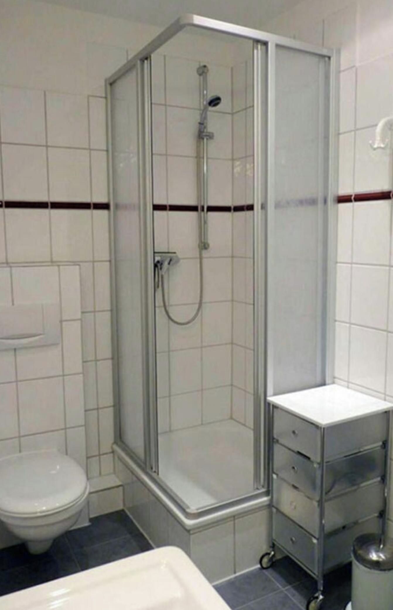 Een badkamer met een douchecabine, een toilet en een wastafel met lades.