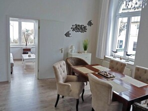 A dining area with a wooden table, four chairs, and a decorative wall with fish and bird wall art. - Hohenzollern Castle - Apartment 11 (Heringsdorf)