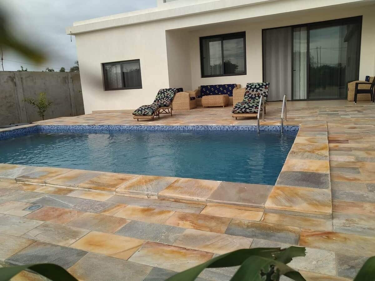 A swimming pool with lounge chairs and a modern house in the background.