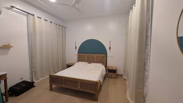 A bedroom with a bed, bedside tables, a ceiling fan, and curtains.