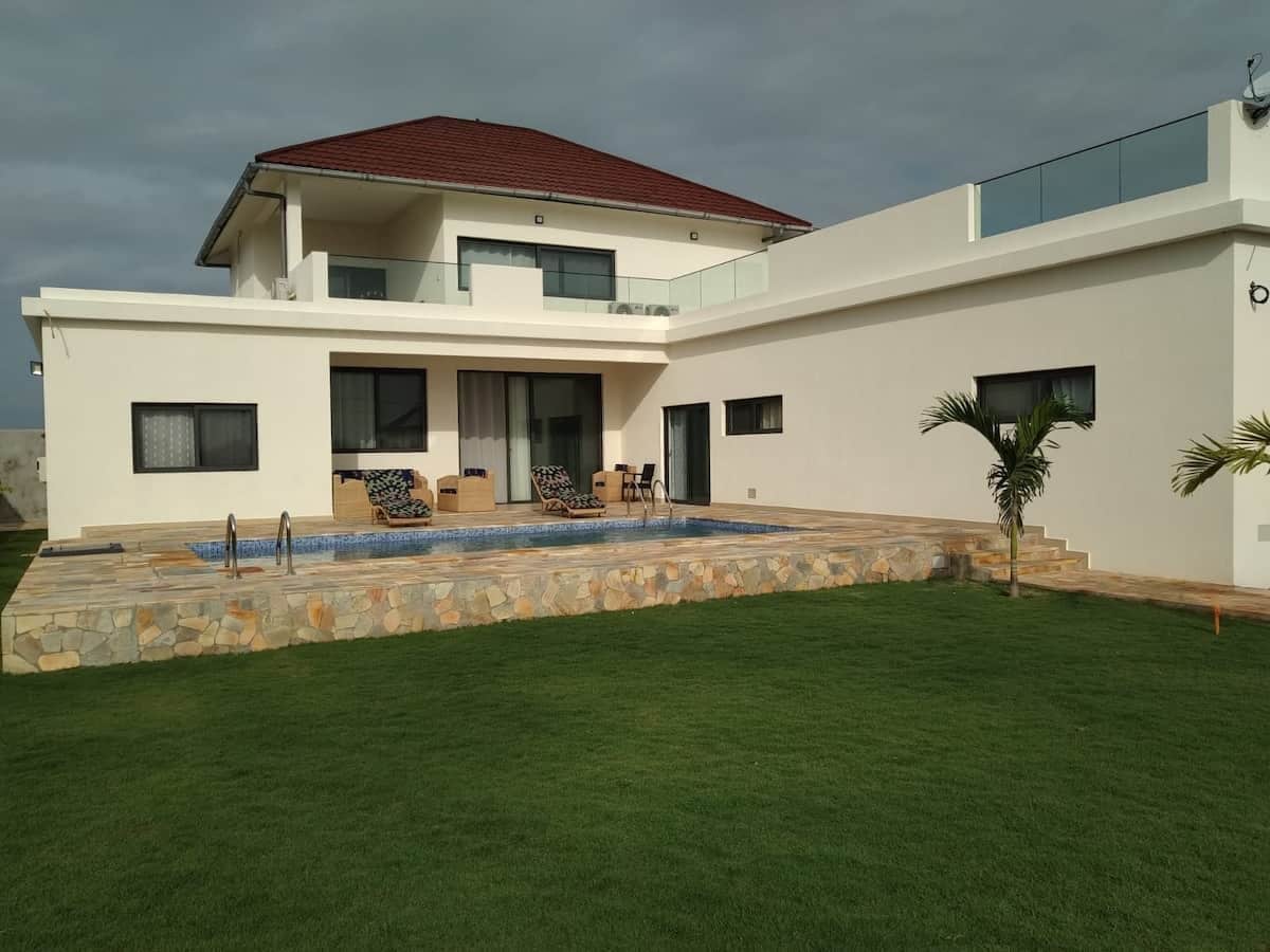A modern two-story house with a swimming pool, a covered patio, and a well-maintained lawn.