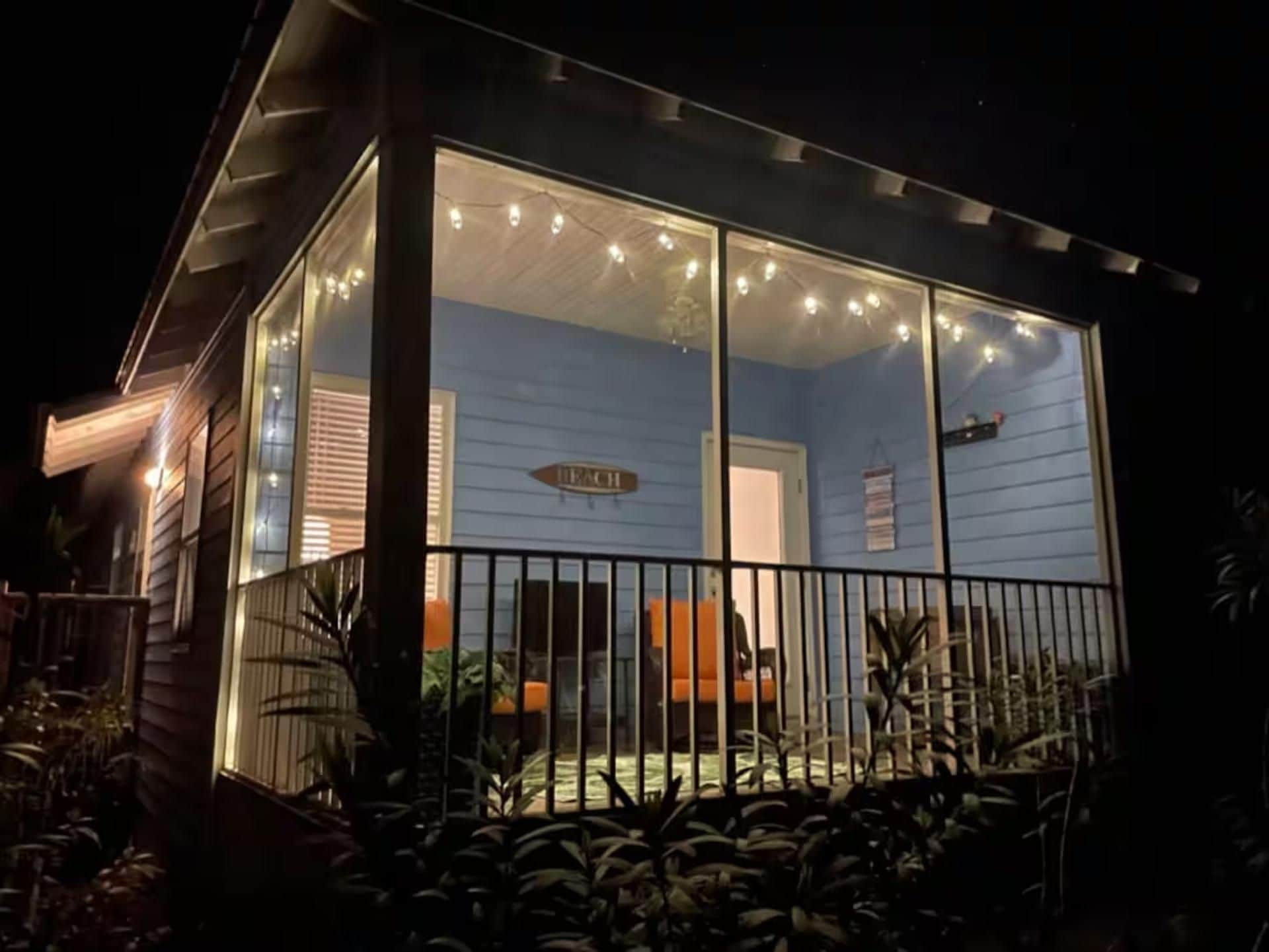 A house with a glass front porch, a sign reading 'Each,' and a small orange chair outside.