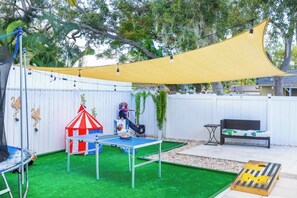 A backyard with a ping pong table, a trampoline, a small play tent, and a bench. - Heated Pool, Games & Family Fun – 15 Min to Siesta Key (Sarasota)