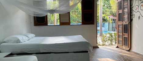 Una habitación con cama, ventana y vista a una piscina.