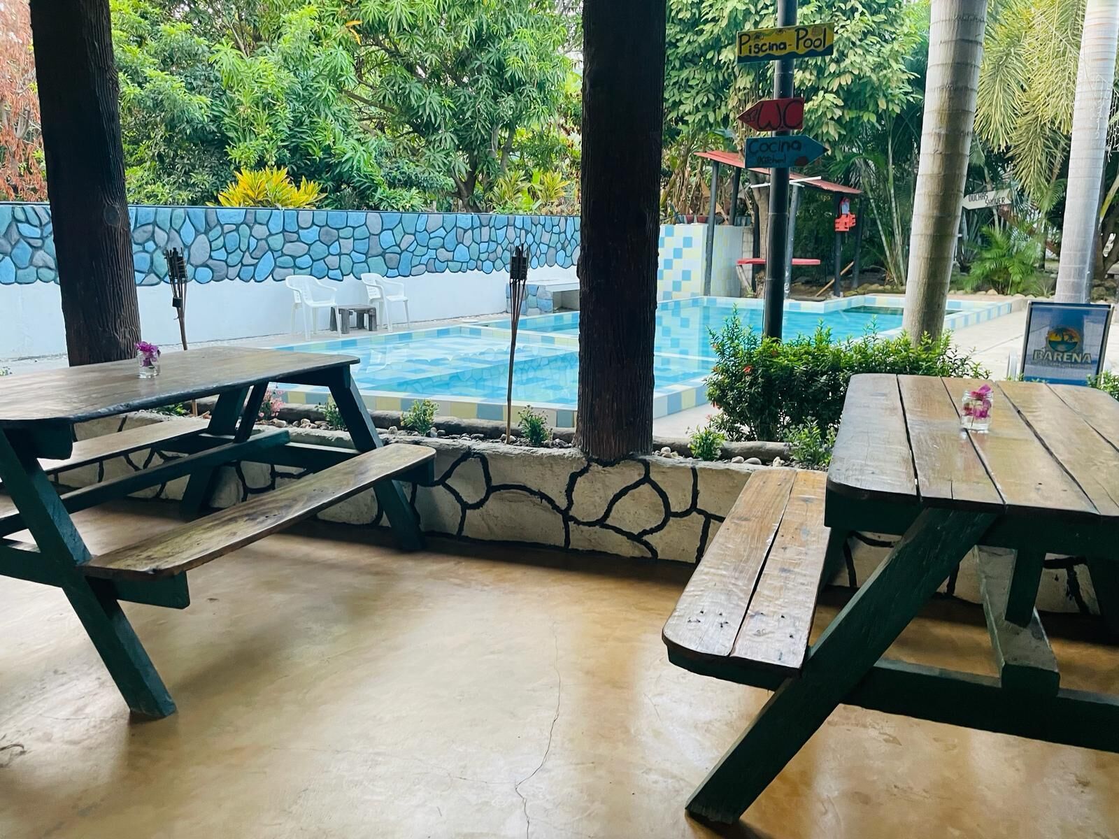 Un espace extérieur aménagé avec des tables de pique-nique, une piscine et un mur en pierre.