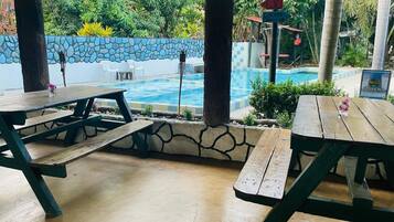 Un espace extérieur aménagé avec des tables de pique-nique, une piscine et un mur en pierre.
