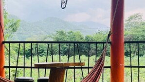Uma rede, uma mesa e vista para uma paisagem montanhosa.