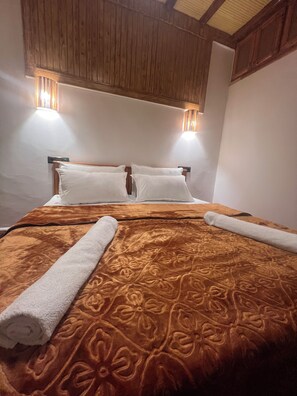 A hotel room with a bed, two wall-mounted lamps, and a wooden ceiling.