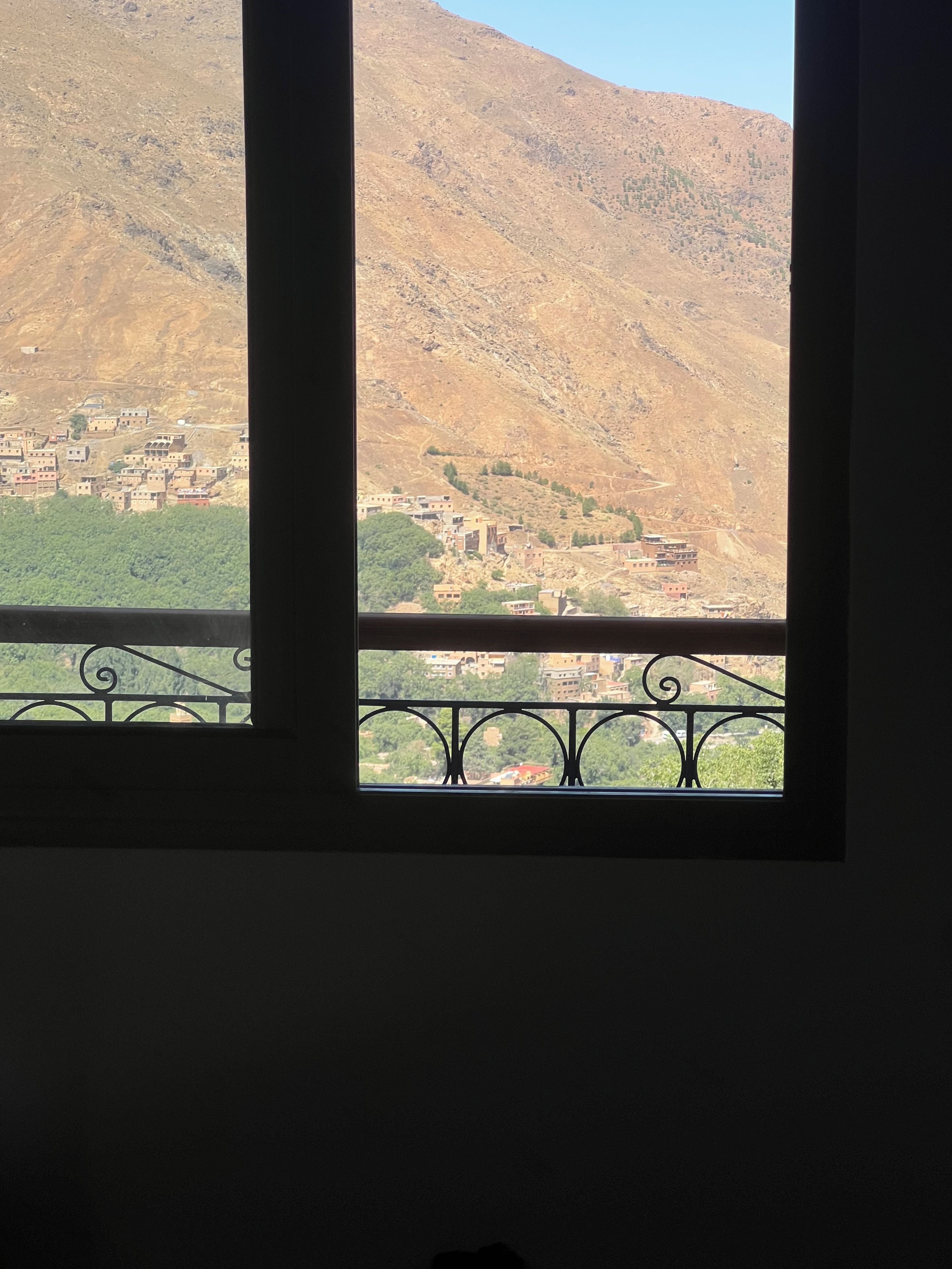 A window view of a mountainous landscape with a village below.