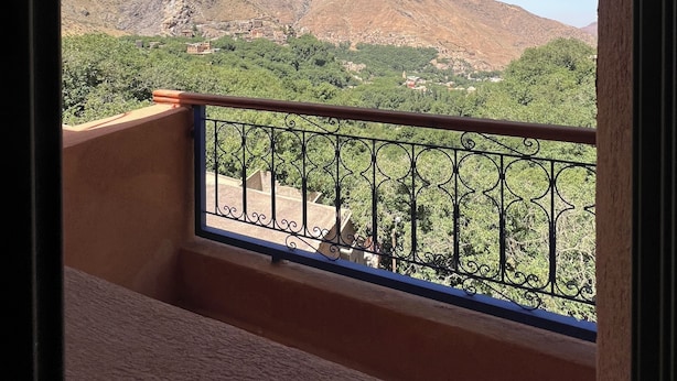 A balcony with a metal railing overlooking a mountainous landscape.