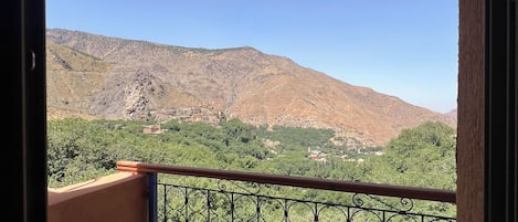 Un balcón con barandilla de metal que da a un paisaje montañoso.