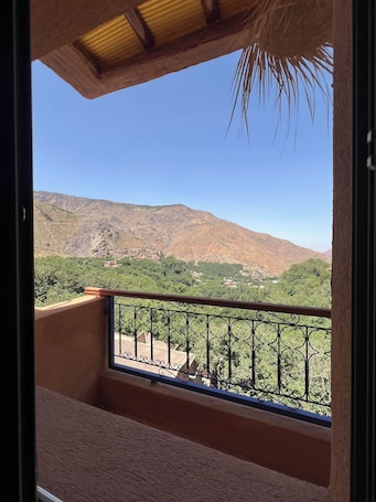 A balcony with a metal railing overlooking a mountainous landscape.