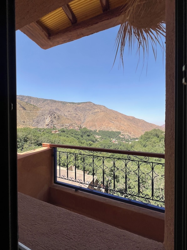 A balcony with a metal railing overlooking a mountainous landscape.