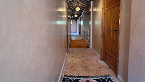 A corridor with a patterned carpet, wooden door, and a ceiling with a corrugated metal design.
