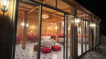 Un bâtiment en bois doté de grandes portes vitrées, d’un éclairage intérieur et d’un revêtement de sol à motifs.