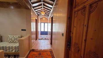 Un pasillo con techo de madera, alfombra estampada y puerta con detalles decorativos.