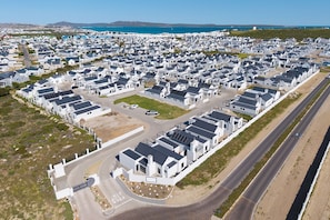 A residential area with modern houses, a road, and a body of water in the background. - Langebaan Wildflower (Langebaan)