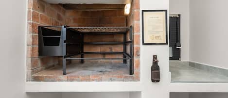 A brick oven with a metal rack, a framed certificate, and a bottle on a counter.