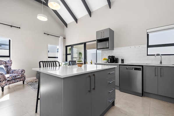 A modern kitchen with grey cabinetry, a white countertop, and a built-in oven.