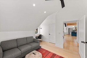 A modern loft apartment with a grey sofa, a small ottoman, and a red rug. - Larkspur Haven, luxury, close to trails & town of CB, has tennis, pickleball! (Crested Butte)