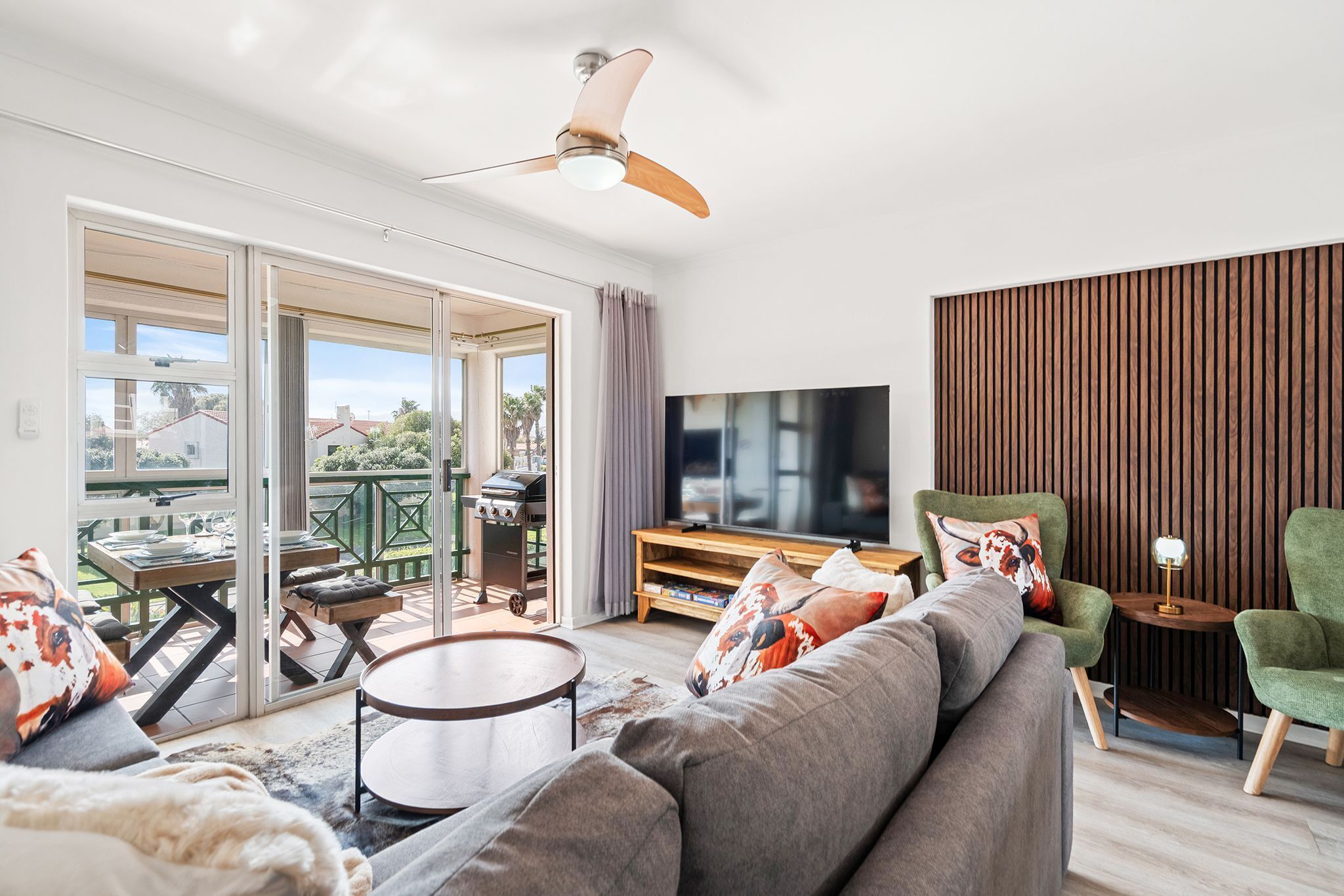Un salon moderne avec un canapé, un téléviseur et un ventilateur de plafond.
