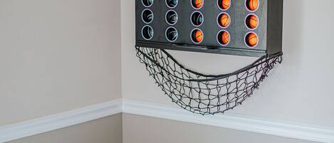 Un panier de basket avec un filet, fixé à un mur avec une plinthe blanche.