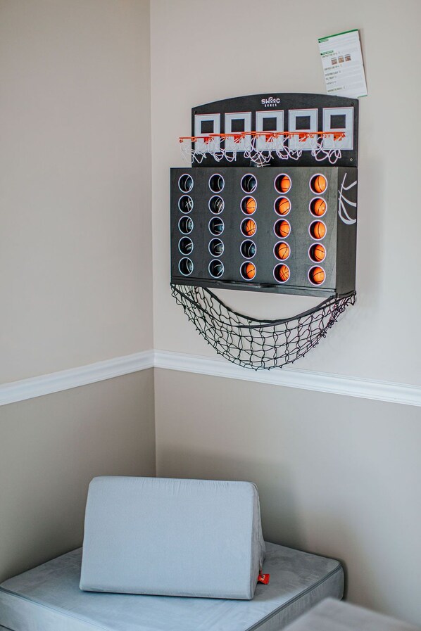 A basketball hoop with a net, mounted on a wall with a white baseboard.