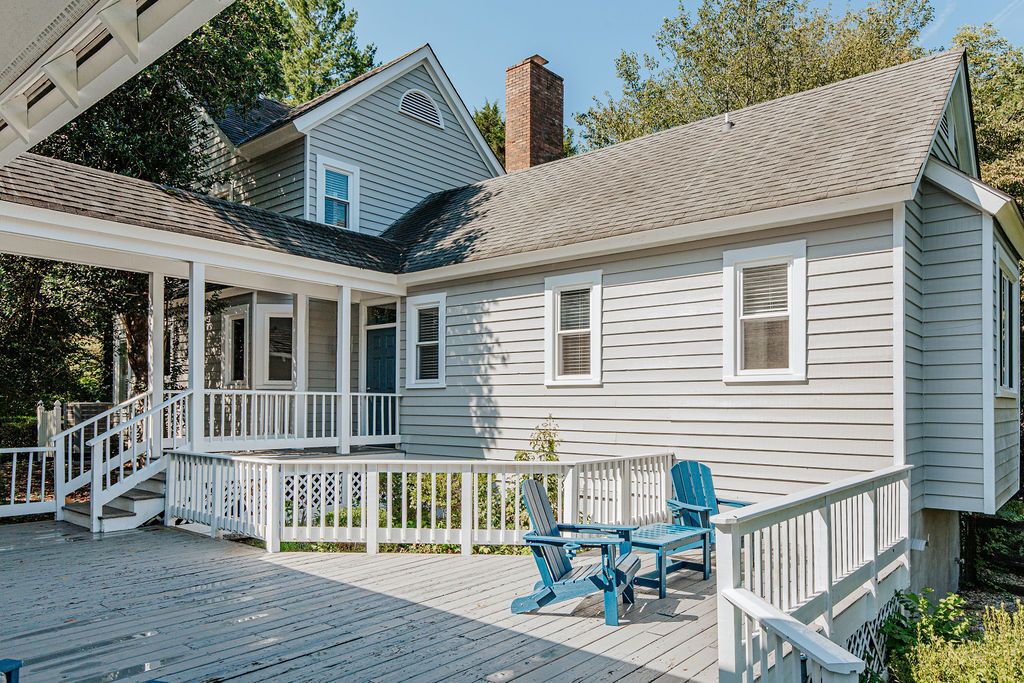 A house with a covered porch, a chimney, and a deck with chairs.