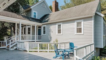 A house with a covered porch, a chimney, and a deck with chairs.