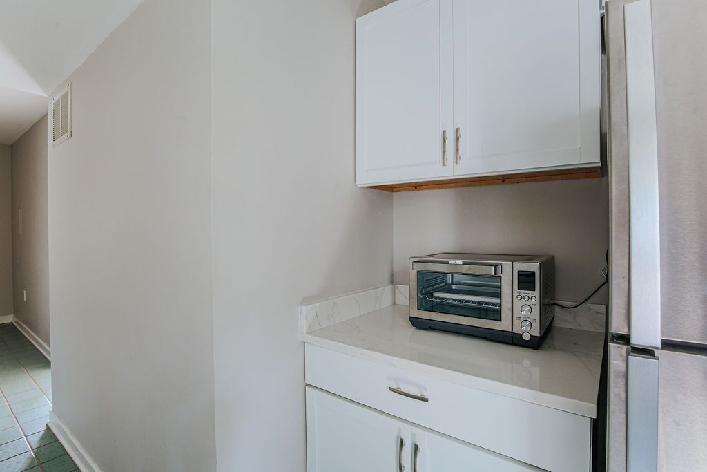 Eine Küche mit weißen Schränken, einem eingebauten Toaster und einem Kühlschrank aus Edelstahl.