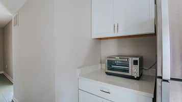 Eine Küche mit weißen Schränken, einem eingebauten Toaster und einem Kühlschrank aus Edelstahl.
