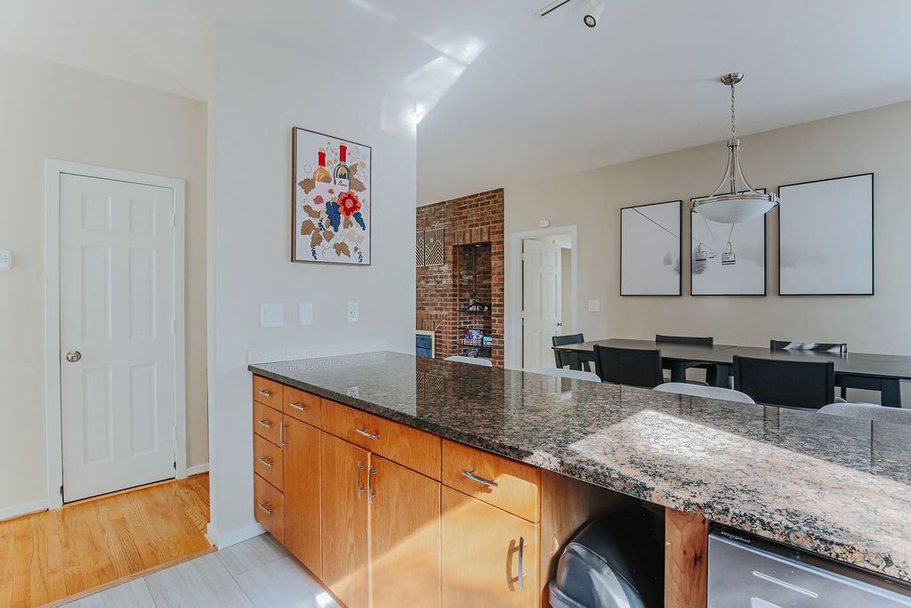 A modern kitchen with granite countertops, wooden cabinets, and a brick backsplash.