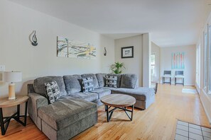 Una sala de estar moderna con un sofá modular, una mesa redonda de centro y una mesita auxiliar.
