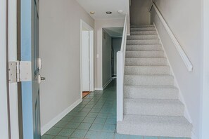 A hallway with a carpeted staircase leading to another room.