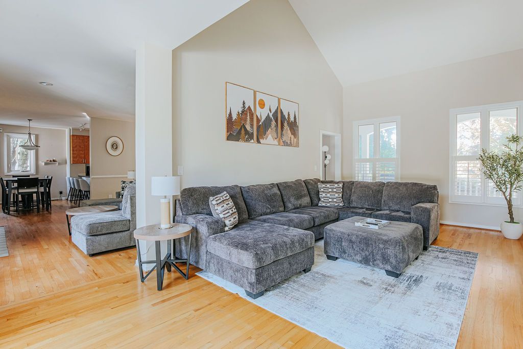 A modern living room with a grey sectional sofa, a round side table, and a large window providing natural light.