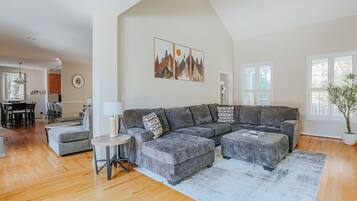 A modern living room with a grey sectional sofa, a round side table, and a large window providing natural light.