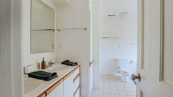 Un baño con lavabo blanco, espejo y retrete.
