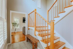 Una escalera de madera con un banco al pie, que lleva a una puerta.
