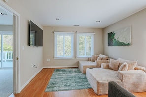A room with a sofa, a television mounted on the wall, and two windows with blinds. - Fore Seasons (Nellysford)