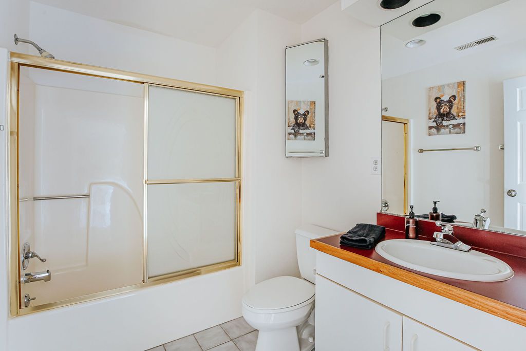 Ein Badezimmer mit Duschkabine, Toilette, Waschbecken und einem Spiegel mit Bärenmotiven.