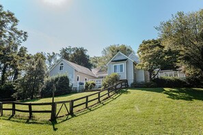 A two-story house with a wooden fence in front, surrounded by trees and a well-maintained lawn. - Fore Seasons (Nellysford)