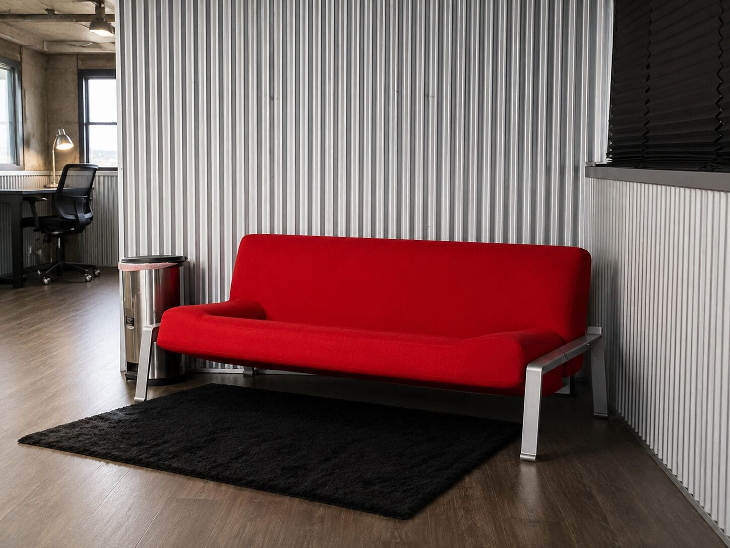 A modern living room with a red sofa, a black rug, and a striped wall.