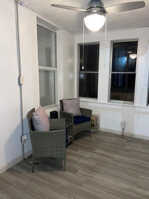 Ein Zimmer mit zwei Korbstühlen, einem Deckenventilator und einem Fenster mit Ausblick.