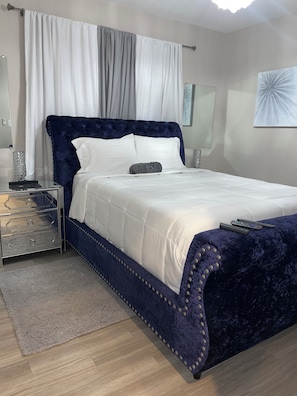 Ein Schlafzimmer mit einem Bett, Nachttischen, einem Teppich und einem Wandbild.