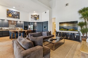 A spacious living area with a modern kitchen, comfortable seating, and artwork on the walls. - 9th Hole Turn.  On the world famous Stadium Course!  Lake, Golf and MNT Views! (La Quinta)
