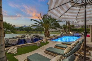 A swimming pool with a waterfall feature, surrounded by lounge chairs and a palm tree. - 9th Hole Turn.  On the world famous Stadium Course!  Lake, Golf and MNT Views! (La Quinta)