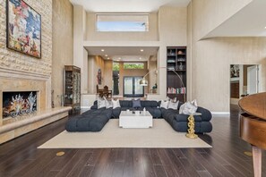 A spacious living room with a sectional sofa, a fireplace, and a large window. - 9th Hole Turn.  On the world famous Stadium Course!  Lake, Golf and MNT Views! (La Quinta)