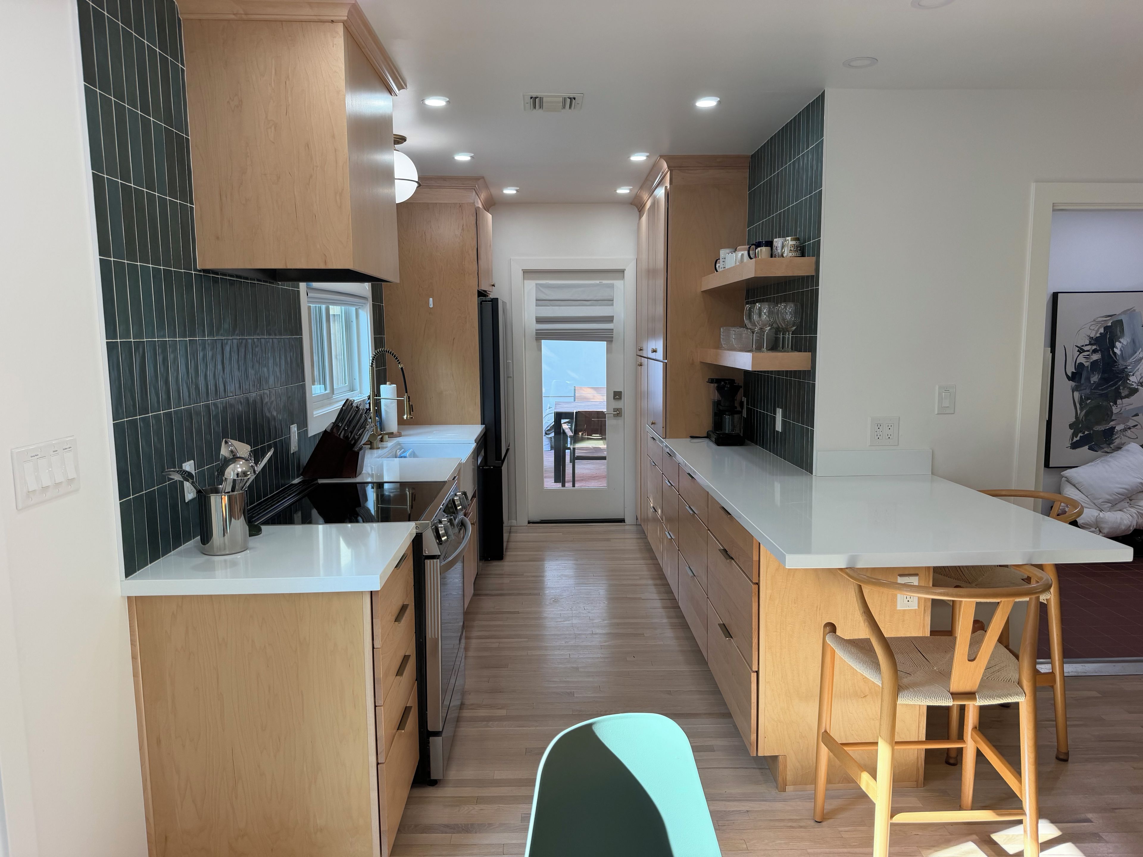 A modern kitchen with wooden cabinets, a central island, and a view to the outside.