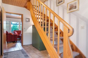 A wooden staircase with a handrail, leading to a landing with a green cabinet and a framed picture on the wall. - Holiday Home Godewind with Terrace, Garden, Wi-Fi & Balcony Near Beach in Otterndorf (Otterndorf)