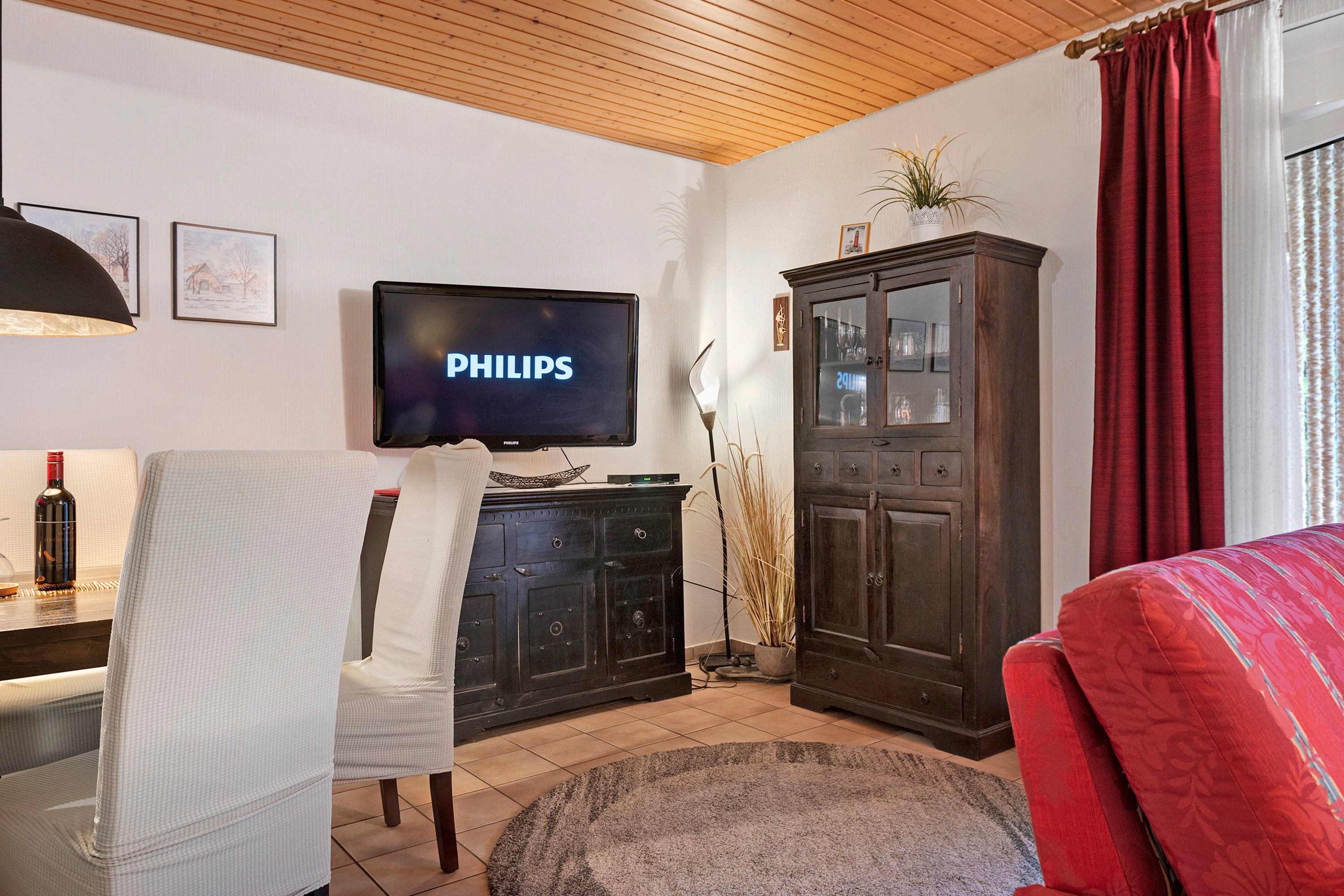 A living room with a television, a cabinet, a chair, and a sofa.